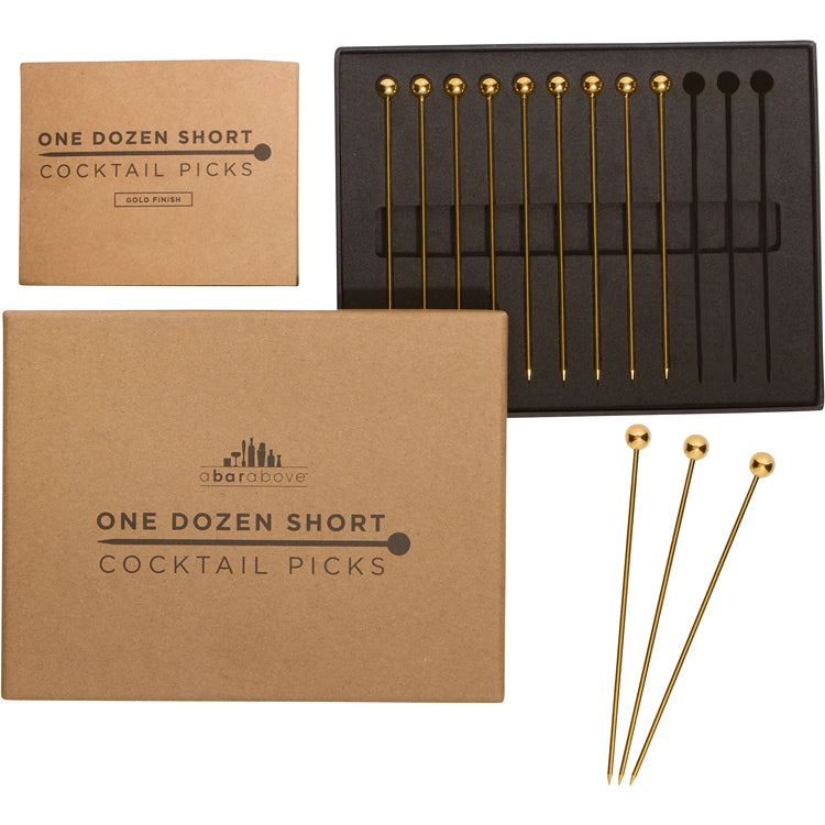 Gold cocktail picks in a black box with a cardboard packaging labeled 'One Dozen Short Cocktail Picks' on a white background.