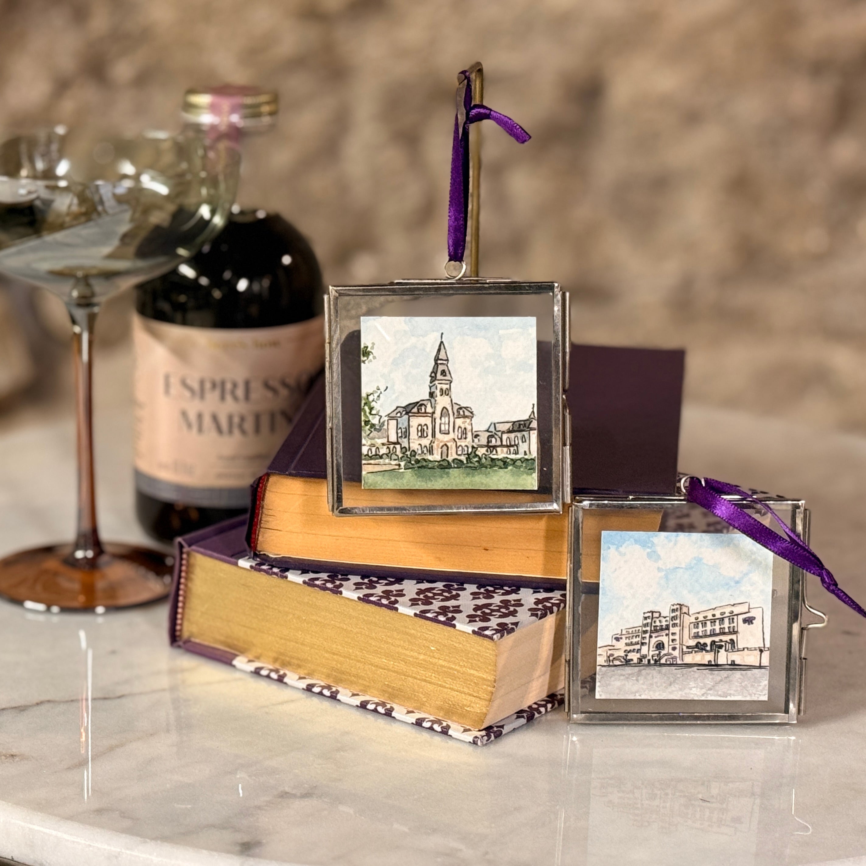 Two small framed pictures on books with a bottle of espresso martini in the background.