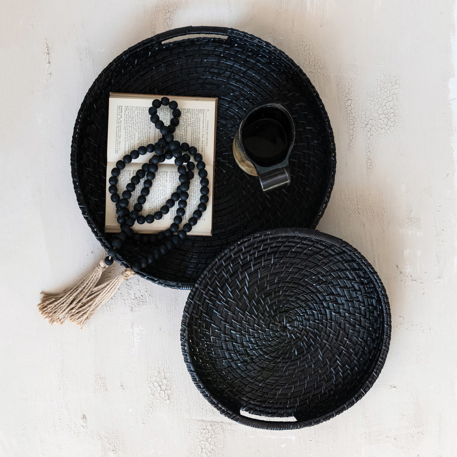 Black woven basket with a tassel, book, and cup on a light background