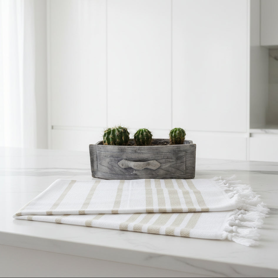 Folded white and beige striped towel with a cactus in a wooden planter on a light background