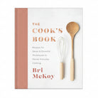 Cookbook titled 'The Cook's Book' by Bri McKay with a wooden spoon and whisk on a white background.
