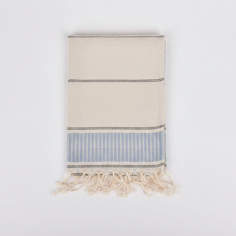 Beige and blue striped towel with tassels on a light gray background