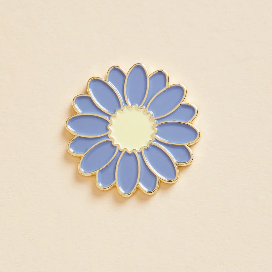 Blue flower-shaped pin on a beige background