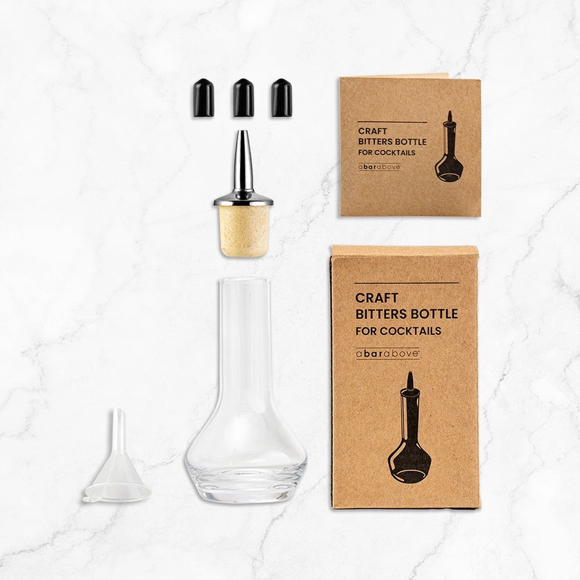 Cocktail bitters bottle with cork stopper and two cardboard boxes on a marble surface