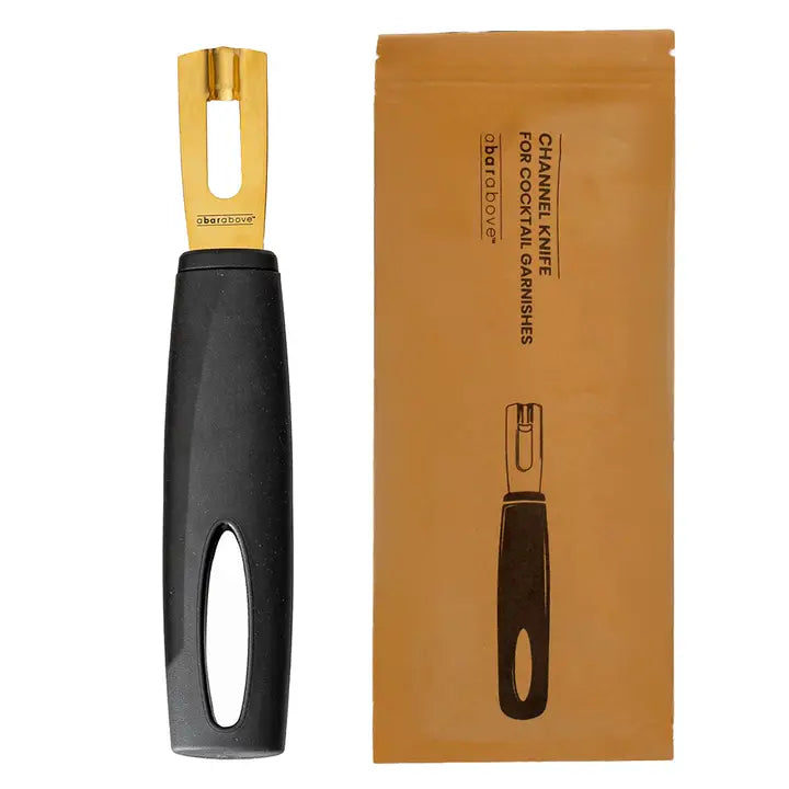 Channel knife with black handle and gold blade next to its packaging on a white background