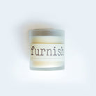 Candle with a label reading 'furnish' on a white background