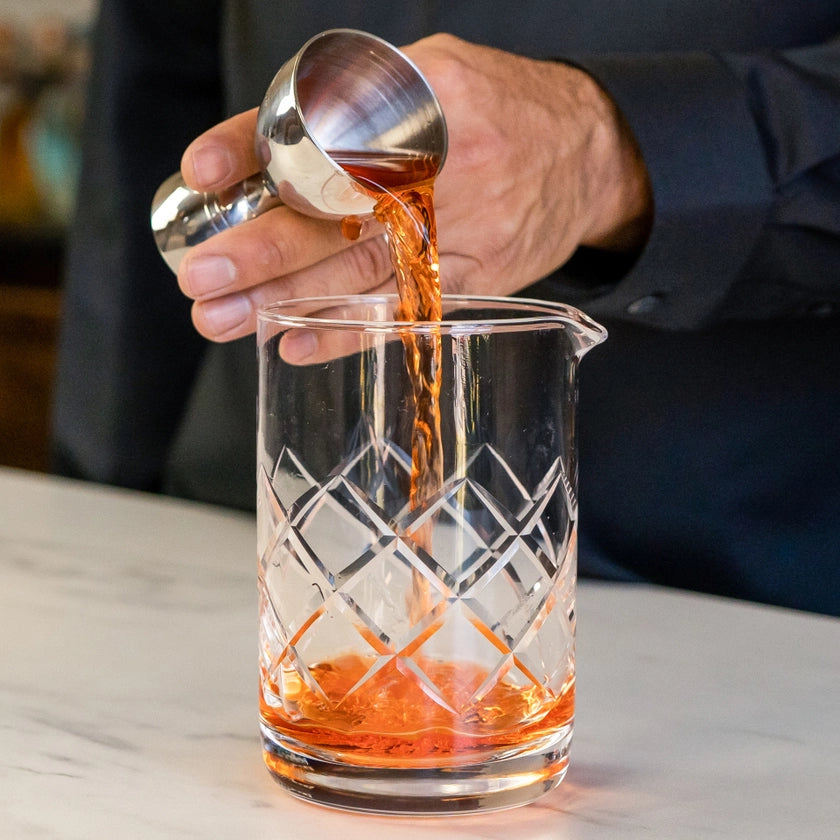 Cocktail being poured from a shaker into a glass with a diamond pattern.