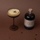 Bottle of Espresso Martini and cocktail with espresso beans on a brown background