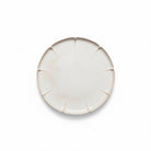 Round ceramic plate with a textured edge on a white background