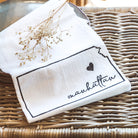 White napkin with 'Manhattan' print on a woven surface