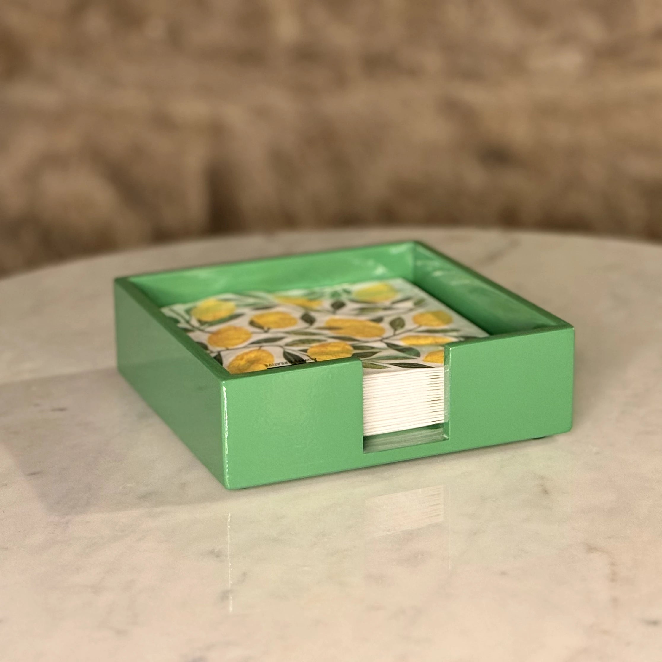 Green box with a stack of cards featuring yellow flowers on a marble surface.