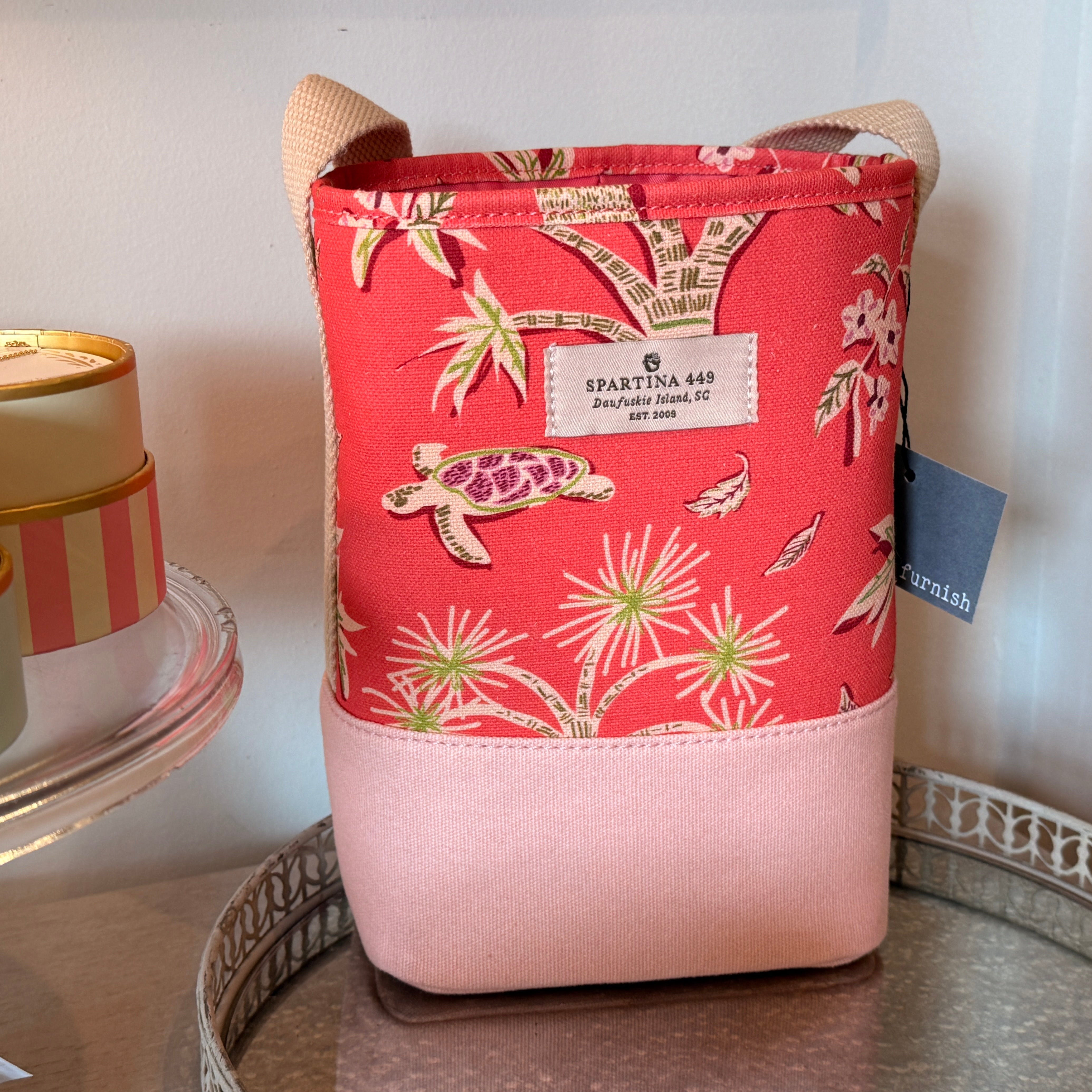 Pink and red fabric bag with floral and turtle design on a white surface