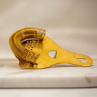 Gold-colored strainer on a light wooden surface