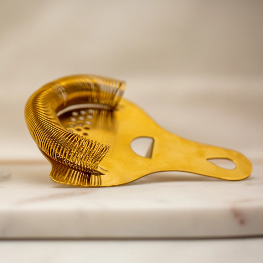 Gold-colored strainer on a light wooden surface