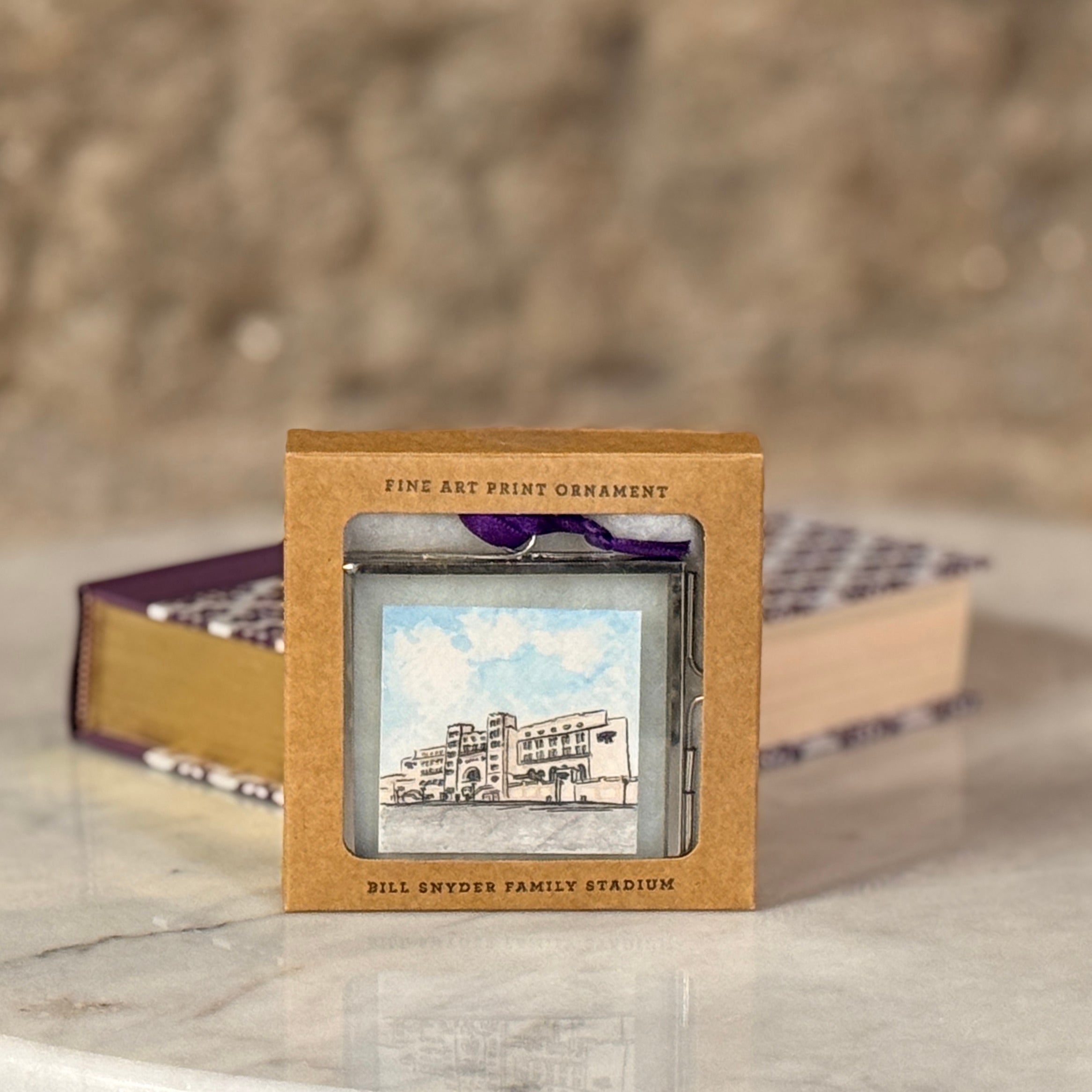 Decorative ornament in a box with 'Bill Snyder Family Stadium' text on a blurred background