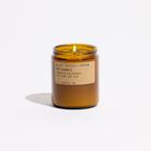 An amber glass jar candle with a lit wick, featuring a beige kraft paper label that reads 'No. 01: Spiced Pumpkin Soy Candle' and 'P.