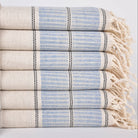 Stack of folded towels with blue and beige stripes on a light background