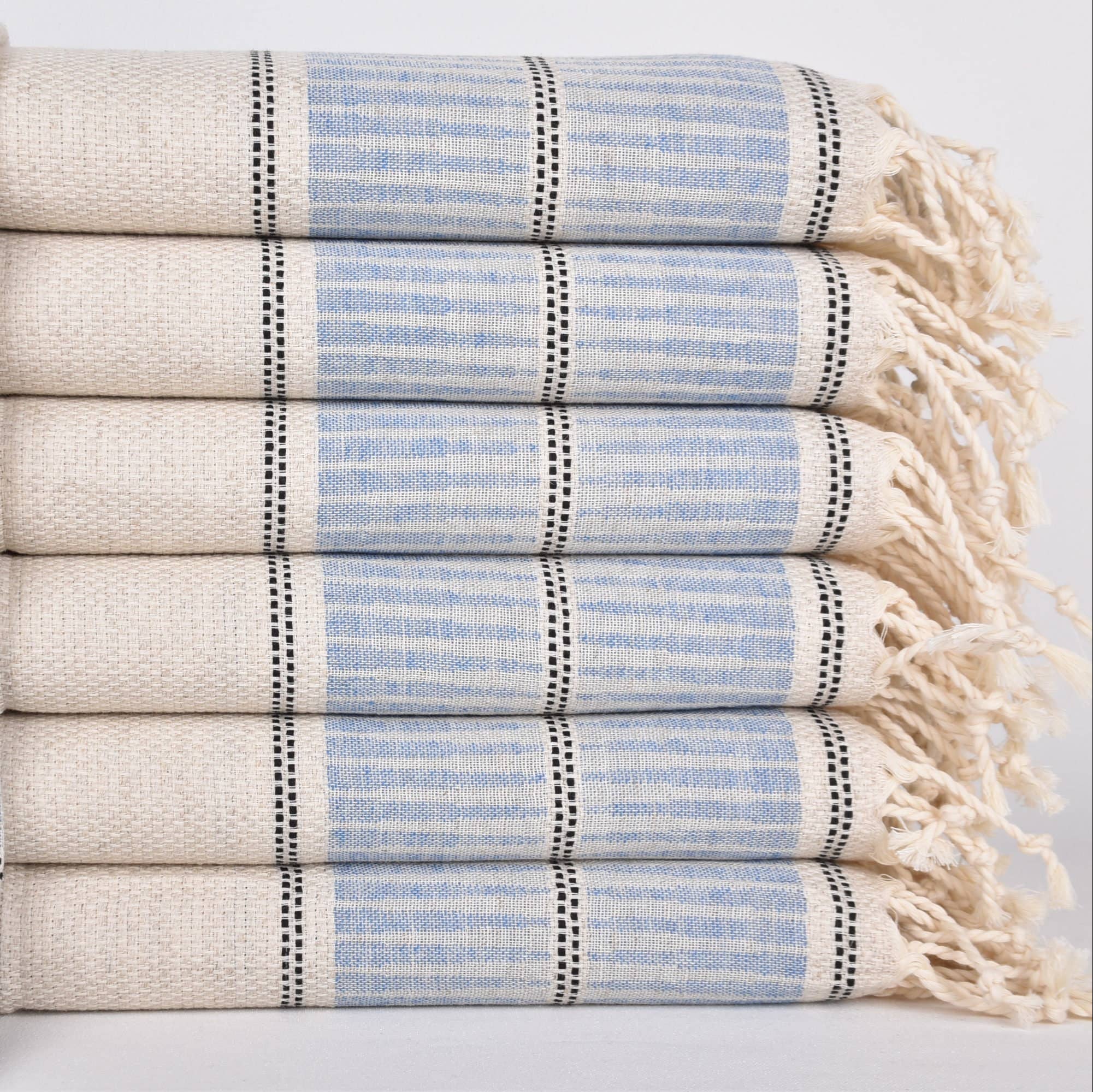 Stack of folded towels with blue and beige stripes on a light background