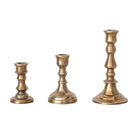 Three brass candle holders of different sizes on a white background