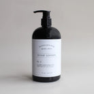 Black bottle of hand lotion with a white label on a light gray background