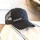 Black quilted cap with 'furnish' logo on a textured surface