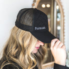 Person wearing a black cap with 'furnish' logo in front of a mirror.