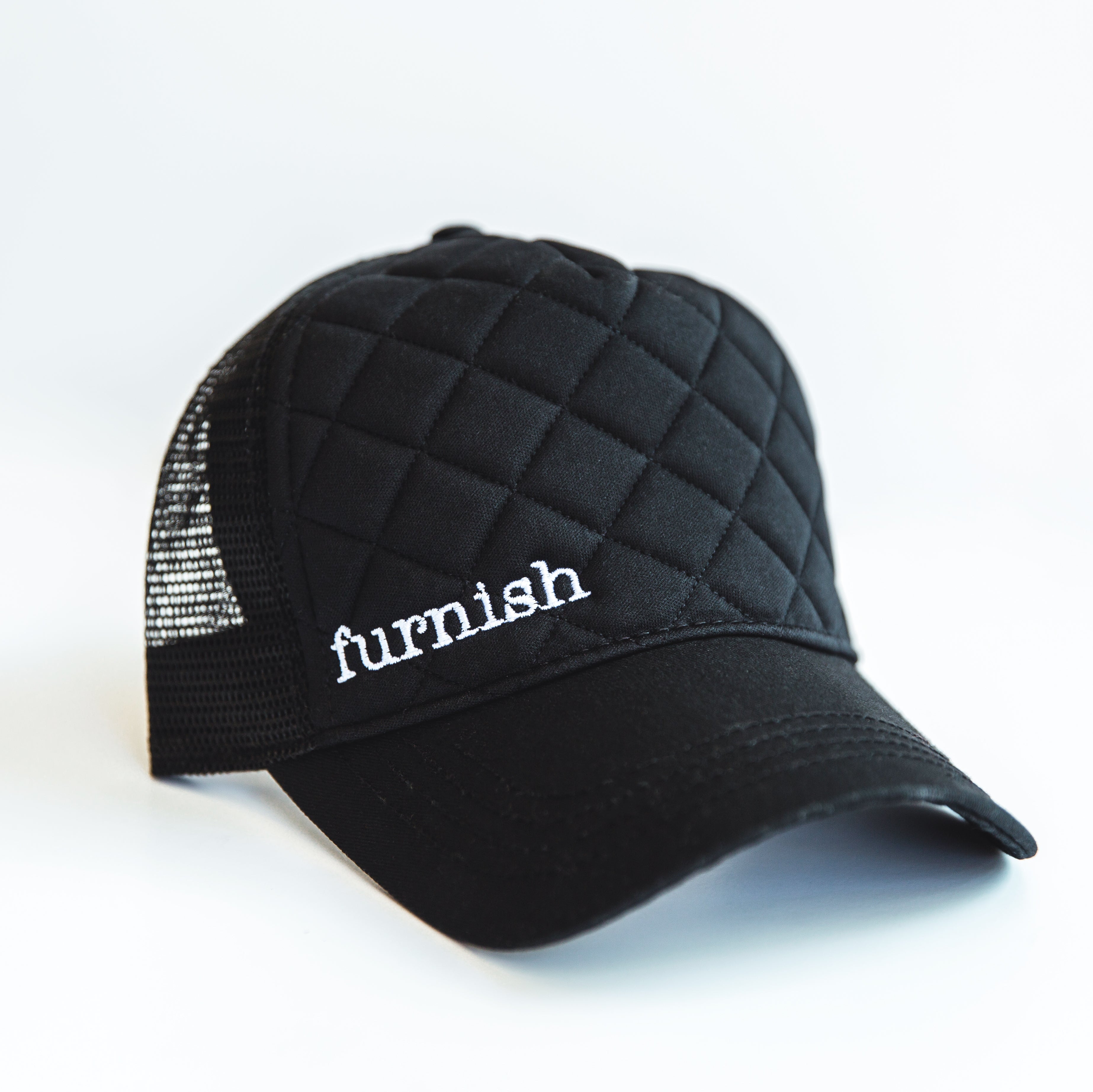 Black quilted cap with 'furnish' branding on a white background