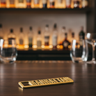 Bar counter with bottles, glasses, and a gold bottle opener in the foreground.