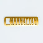 Gold 'Manhattan' bottle opener on a white background