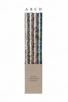 Set of four rolls of floral-patterned gift wrap in a cardboard holder on a white background.
